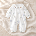 The Collared Cotton Baby Romper — Style 01 studio flat lay on warm ivory linen