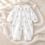 The Collared Cotton Baby Romper — Style 01 studio flat lay on warm ivory linen