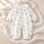 The Collared Cotton Baby Romper — Style 03 studio flat lay on warm ivory linen
