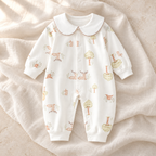 The Collared Cotton Baby Romper — Style 04 studio flat lay on warm ivory linen
