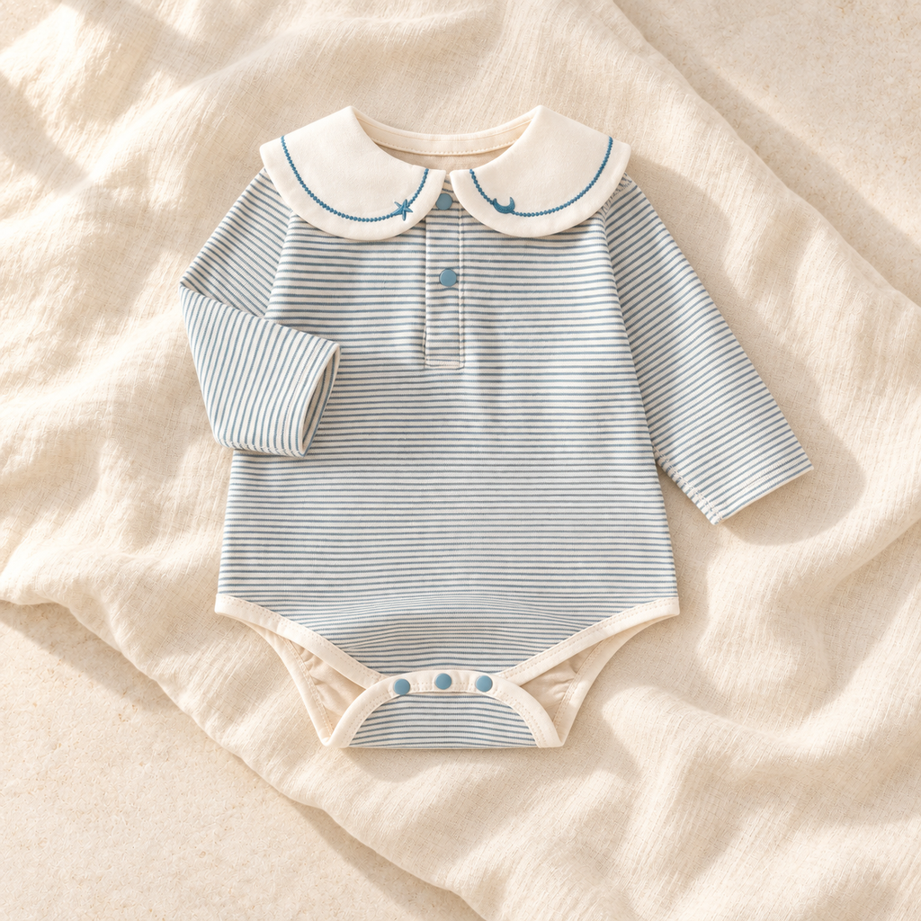 The Sailor Stripe Cotton Romper — blue-B studio flat lay on warm ivory linen