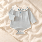 The Sailor Stripe Cotton Romper — blue-B studio flat lay on warm ivory linen