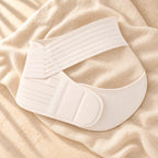 The white multi-part maternity support belly belt photographed on warm cream linen