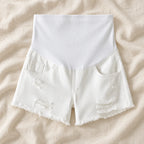 Distressed Maternity Denim Shorts — Style White — full belly panel — on cream linen