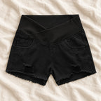 Distressed Maternity Denim Shorts — Style Black — crossover waist — on cream linen
