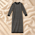 The black long-sleeve maternity maxi knit dress with ivory horizontal stripes photographed on warm cream linen