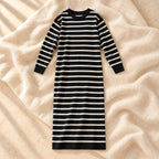 The black long-sleeve maternity maxi knit dress with ivory horizontal stripes photographed on warm cream linen