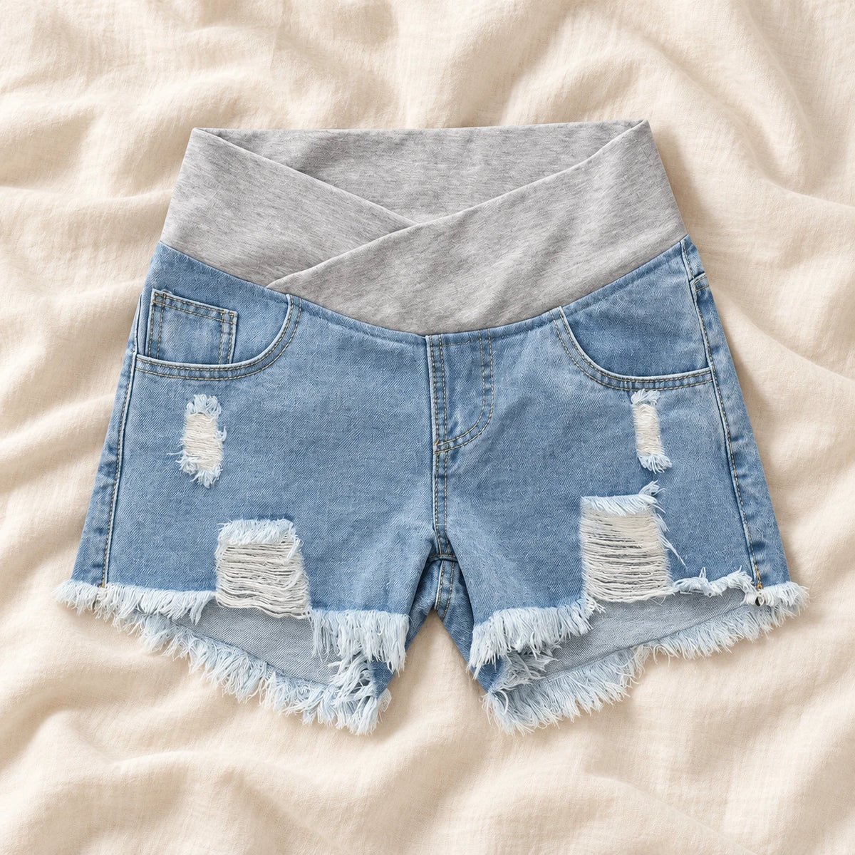 Distressed Maternity Denim Shorts — Style Light Blue — crossover waist — on cream linen