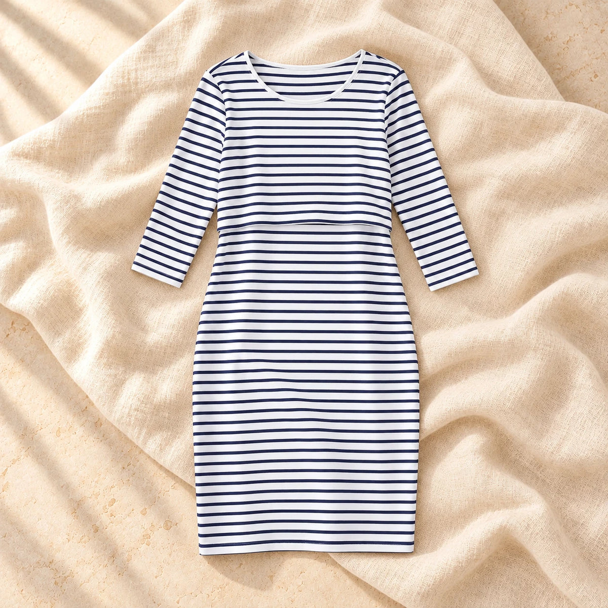 Striped Three-Quarter Sleeve Nursing Dress in WHITE, photographed on warm cream linen