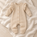 Beige button-knit baby romper on ivory linen