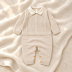 Cream cable knit baby romper with white collar on ivory linen