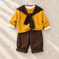 Yellow button knit cardigan and coordinating trousers, styled with a brown scarf