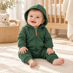 Baby wearing The Hooded Zip Baby Romper in a warm nursery