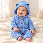 Baby wearing The Hooded Knit Baby Romper in a warm nursery