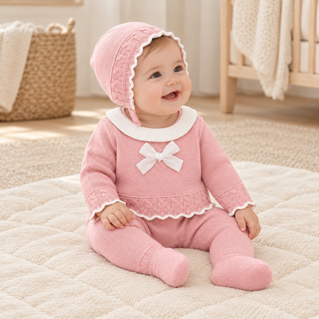 Baby wearing The Blush Knit Three-Piece Set in a warm nursery