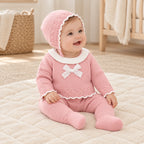 Baby wearing The Blush Knit Three-Piece Set in a warm nursery