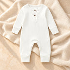 White ribbed baby romper on ivory linen