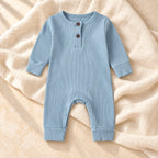 Dusty blue ribbed baby romper on warm ivory linen