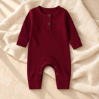 Burgundy ribbed baby romper on warm ivory linen