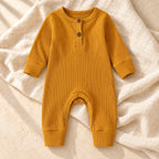 Mustard ribbed baby romper on warm ivory linen