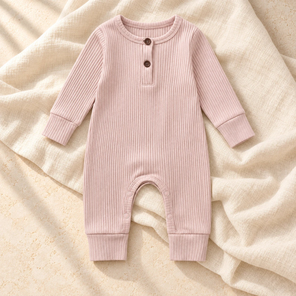 Blush pink ribbed baby romper on warm ivory linen