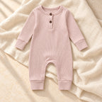 Blush pink ribbed baby romper on warm ivory linen