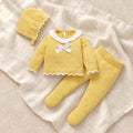 Mustard knit baby bonnet, sweater and footed leggings on ivory linen