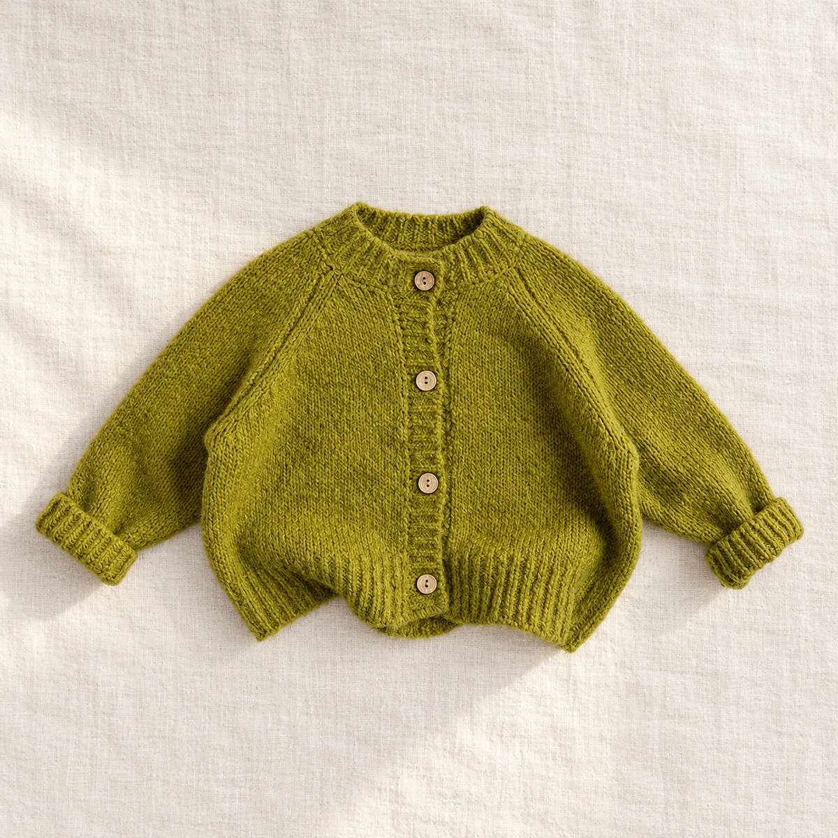 The Cozy Button Knit Cardigan — Green, laid flat on ivory linen