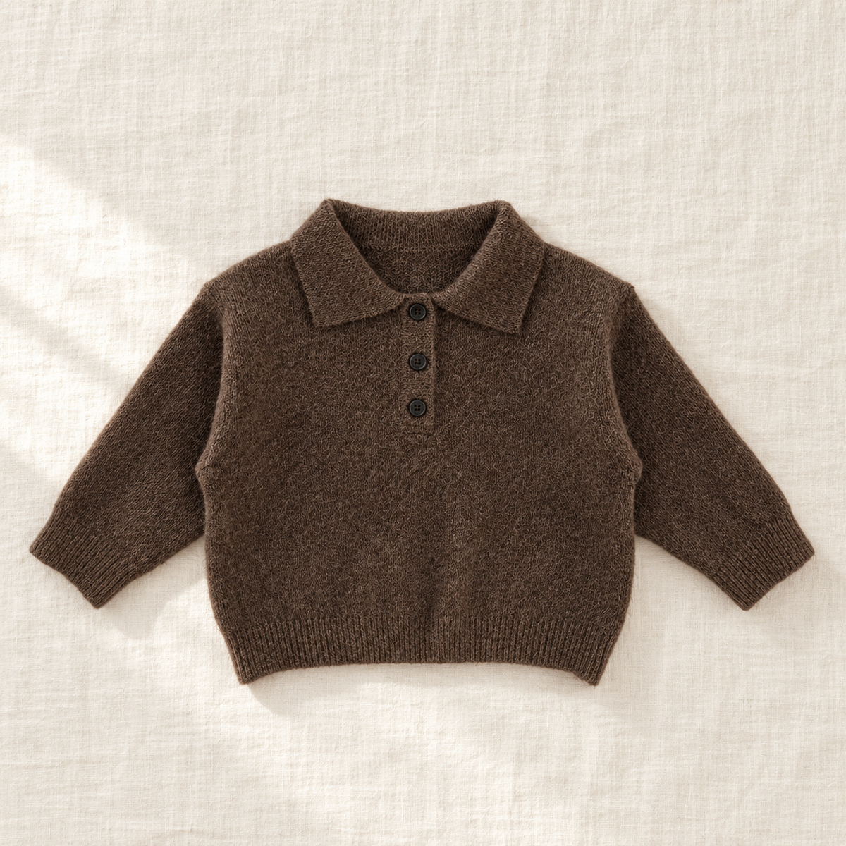 The Long-Sleeve Knit Polo — Coffee, laid flat on ivory linen