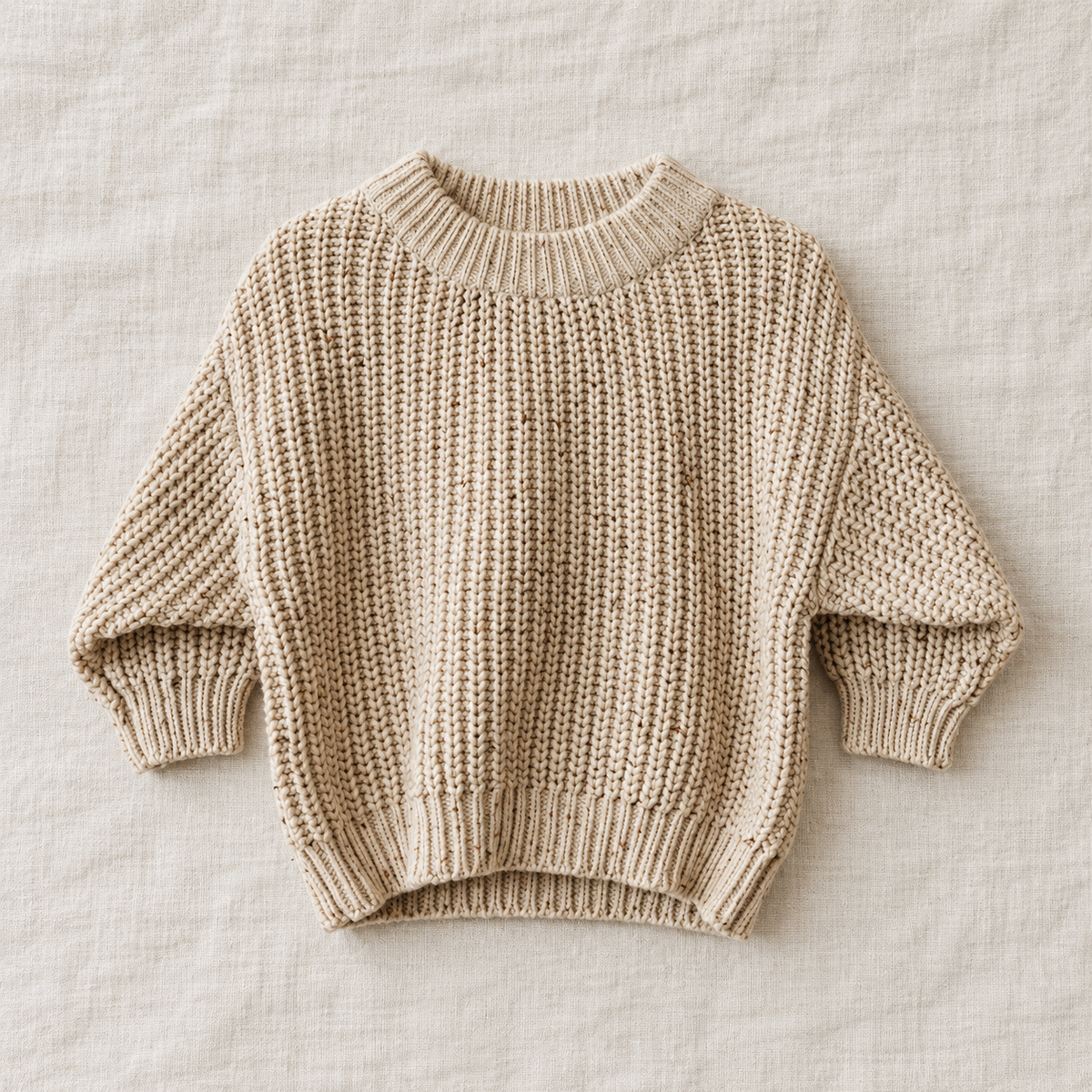The Relaxed Rib Knit Sweater — Apricot Dots, laid flat on ivory linen