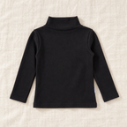 The High-Neck Layering Top — Black, laid flat on ivory linen