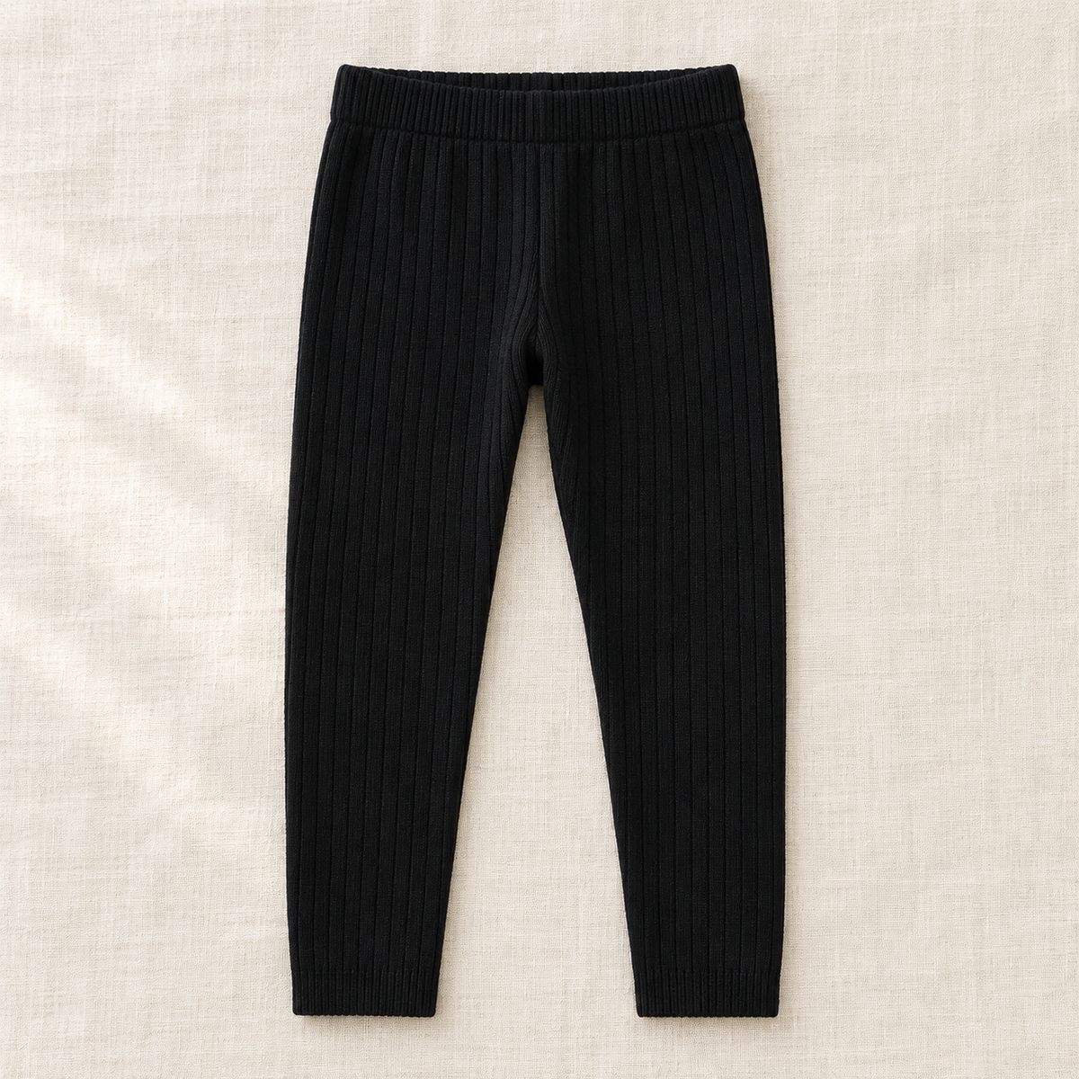 The Everyday Rib Knit Leggings — Black, laid flat on ivory linen