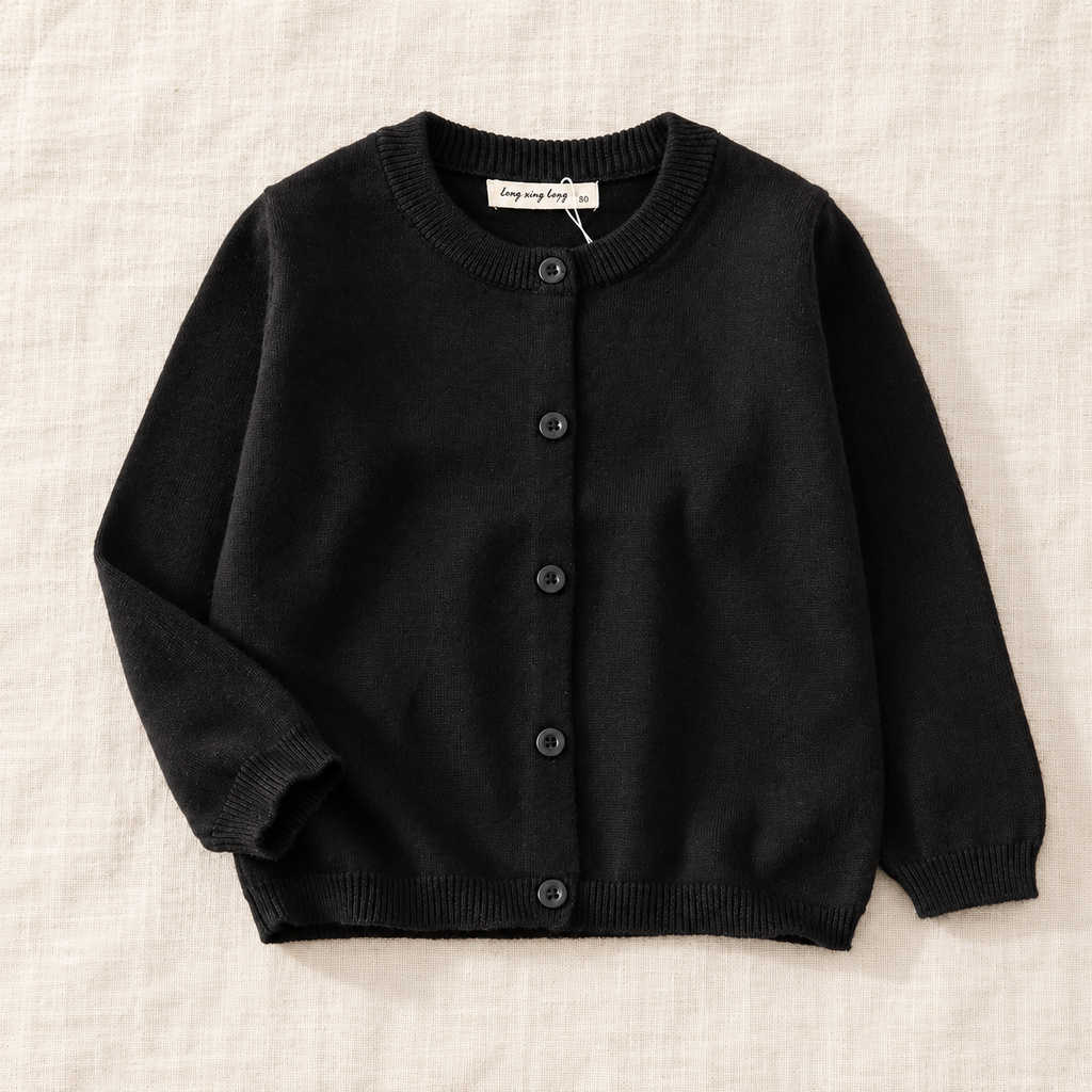The Simple Button Knit Cardigan — Black, laid flat on ivory linen