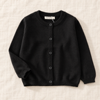The Simple Button Knit Cardigan — Black, laid flat on ivory linen