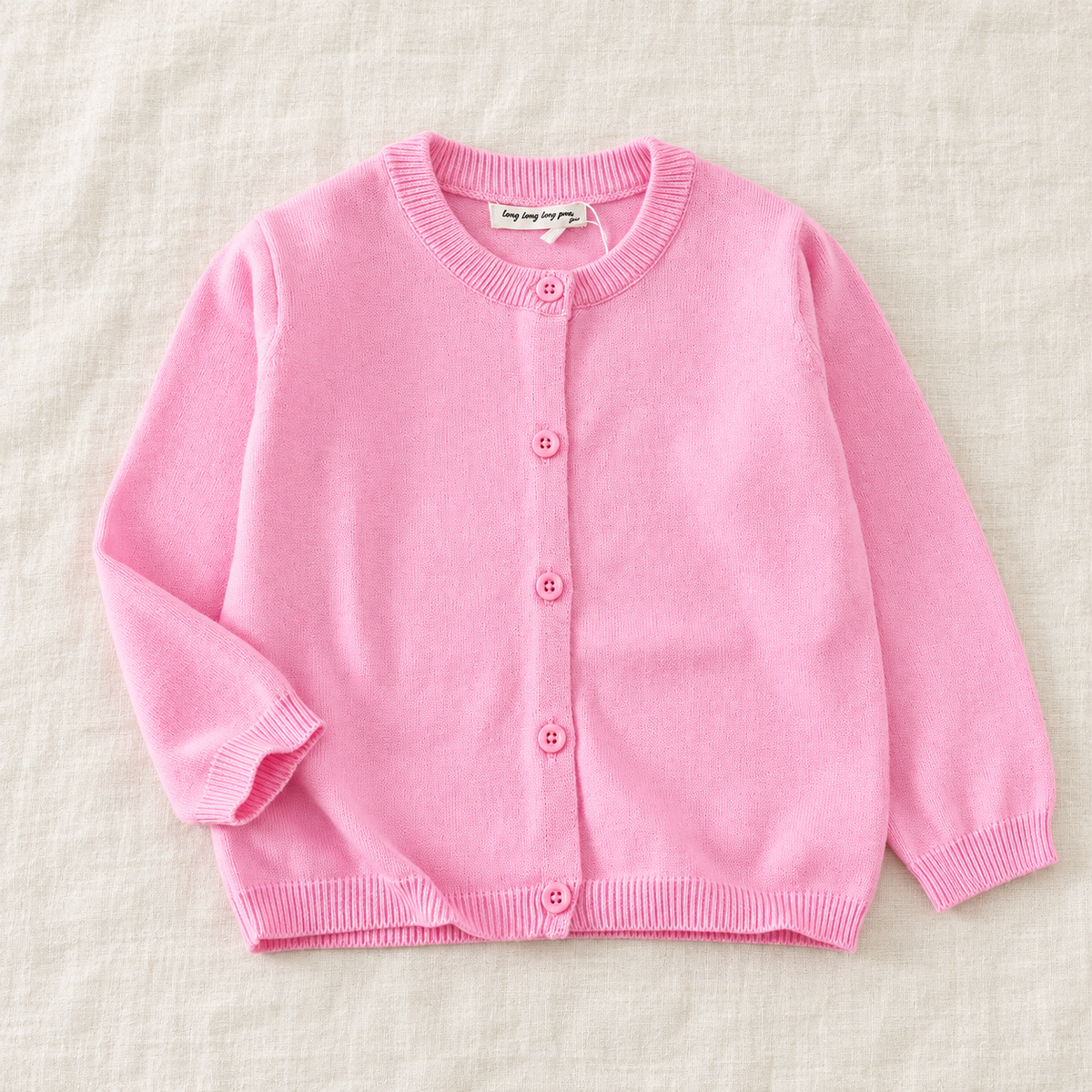 The Simple Button Knit Cardigan — Pink, laid flat on ivory linen