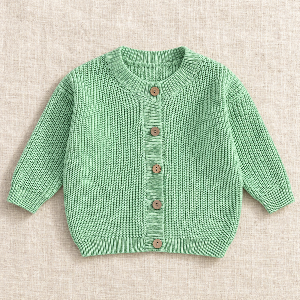 The Ribbed Button Knit Cardigan — Green, laid flat on ivory linen