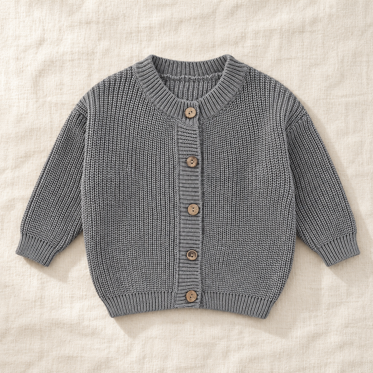 The Ribbed Button Knit Cardigan — Gray, laid flat on ivory linen