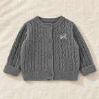 The Soft Cable Knit Cardigan — Gray, laid flat on ivory linen