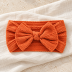 The Everyday Bow Baby Headband studio photograph on ivory linen