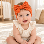 Baby wearing The Everyday Bow Baby Headband in a warm nursery