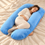 Light Blue U-shaped pregnancy pillow in use by a woman on a cream linen bed